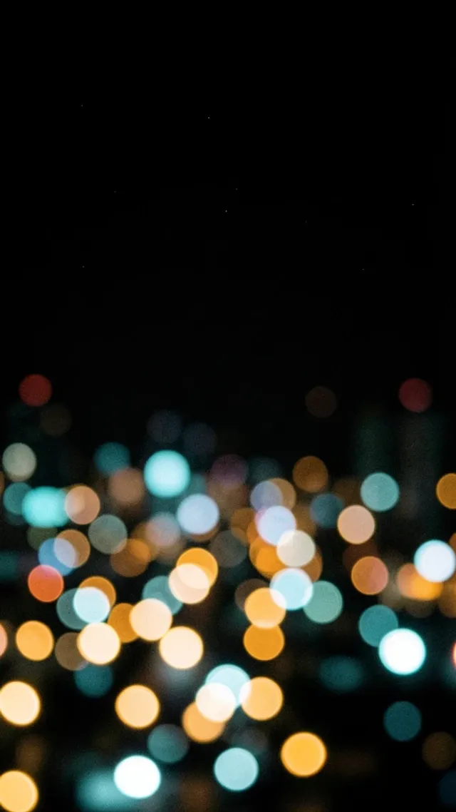 A defocused city lights bokeh field phone wallpaper on deep black