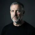 A moody single-softbox studio headshot on charcoal